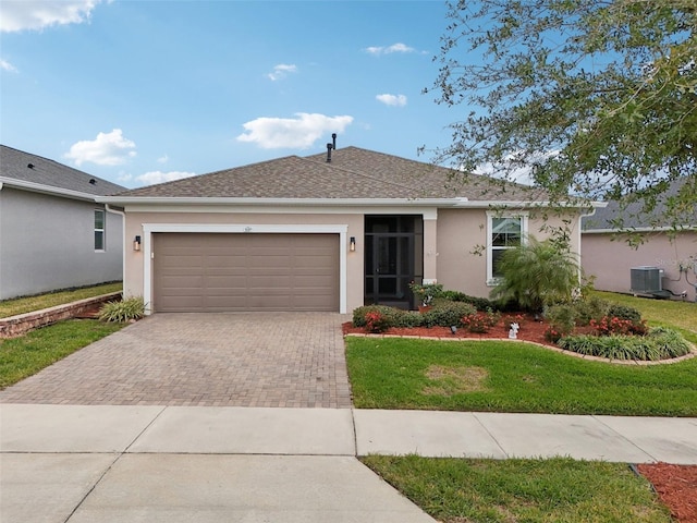 ranch-style home with a garage, a front lawn, and central air condition unit