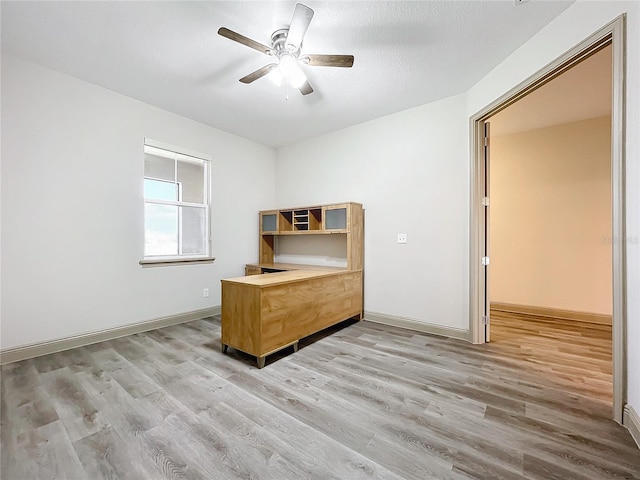 unfurnished office with ceiling fan, light hardwood / wood-style flooring, and a textured ceiling