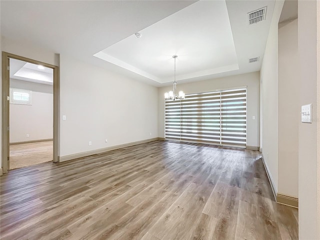 interior space featuring hardwood / wood-style floors, a tray ceiling, and an inviting chandelier