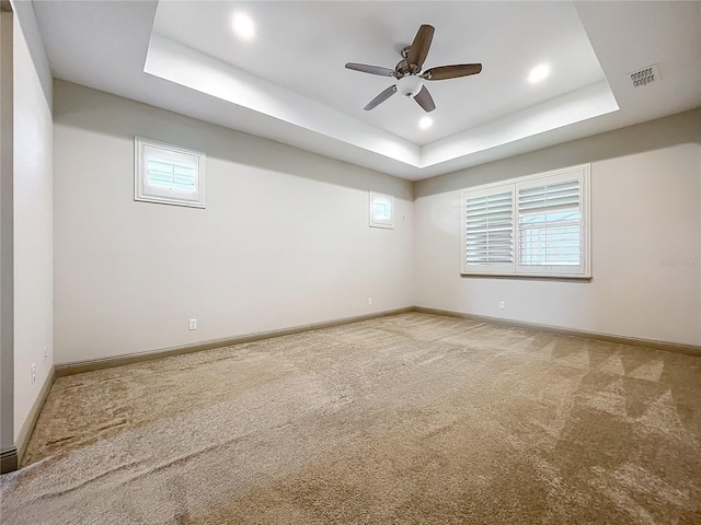 unfurnished room featuring carpet flooring, a tray ceiling, and ceiling fan