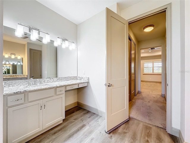 bathroom with ceiling fan, vanity, and wood-type flooring