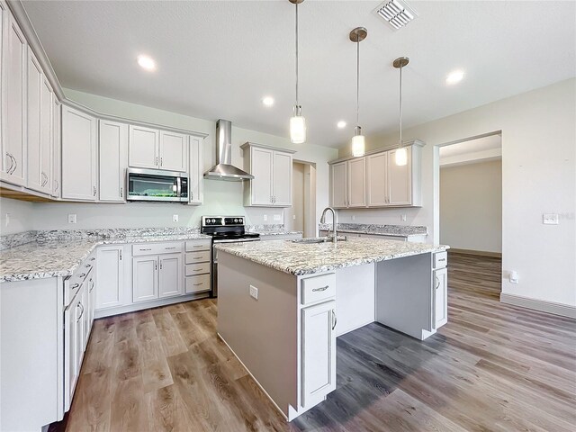 kitchen featuring white cabinets, stainless steel appliances, a kitchen island with sink, and wall chimney range hood