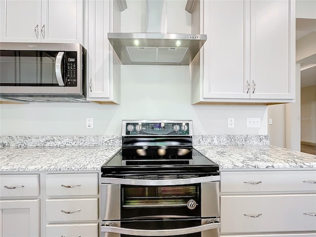 kitchen featuring stainless steel appliances, white cabinetry, and wall chimney range hood