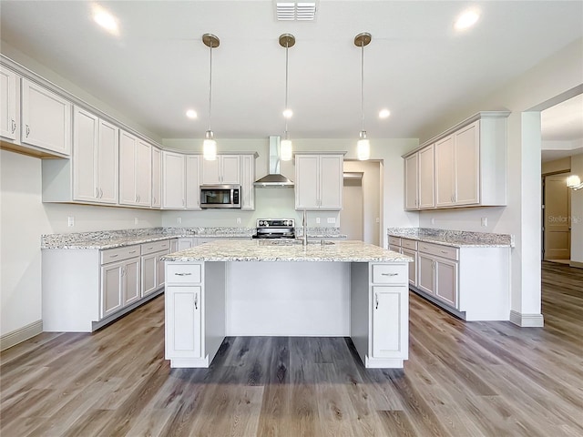 kitchen with pendant lighting, a kitchen island with sink, wall chimney exhaust hood, dark hardwood / wood-style floors, and range with electric stovetop