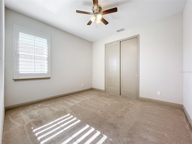 unfurnished bedroom featuring light colored carpet, a closet, and ceiling fan