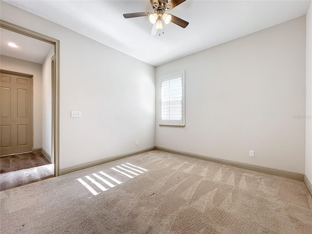 empty room featuring ceiling fan and light colored carpet