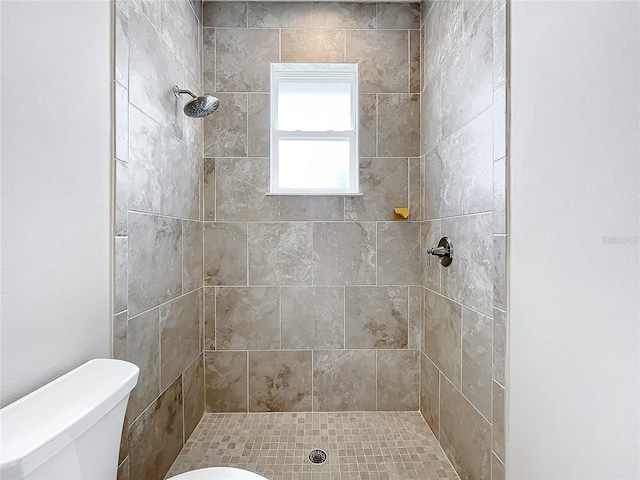 bathroom featuring a tile shower and toilet