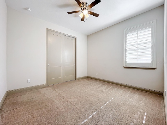 unfurnished bedroom with ceiling fan, light carpet, and a closet