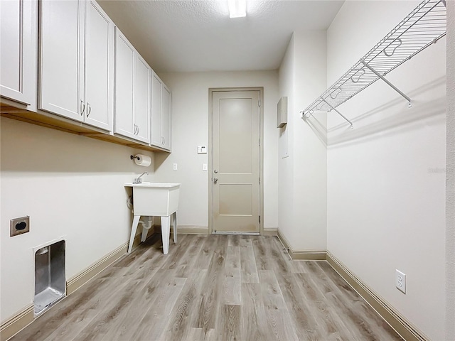 clothes washing area featuring cabinets, a textured ceiling, light hardwood / wood-style floors, and electric dryer hookup