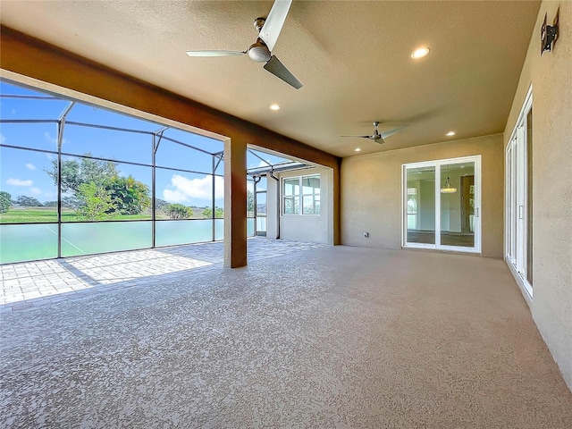 unfurnished sunroom featuring ceiling fan and a water view