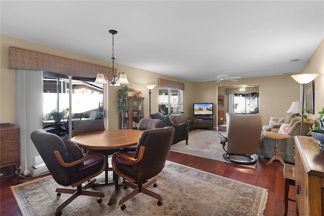 dining space featuring ceiling fan with notable chandelier and dark hardwood / wood-style flooring