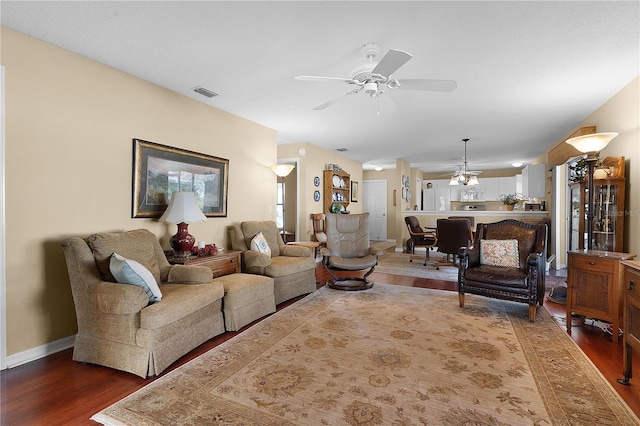 living room featuring ceiling fan with notable chandelier and dark hardwood / wood-style floors