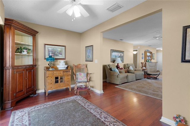 living room with ceiling fan and dark wood-type flooring