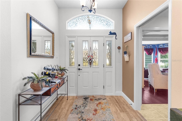 foyer with light hardwood / wood-style flooring, a healthy amount of sunlight, and a notable chandelier