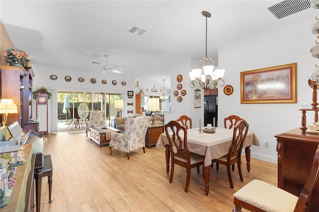 dining space with ceiling fan with notable chandelier and light wood-type flooring