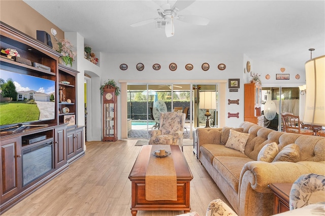 living room with ceiling fan, light hardwood / wood-style floors, and vaulted ceiling