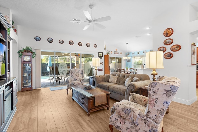 living room featuring light wood-type flooring, vaulted ceiling, ceiling fan, and a healthy amount of sunlight