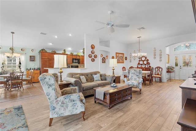 living room featuring ceiling fan with notable chandelier and light hardwood / wood-style floors