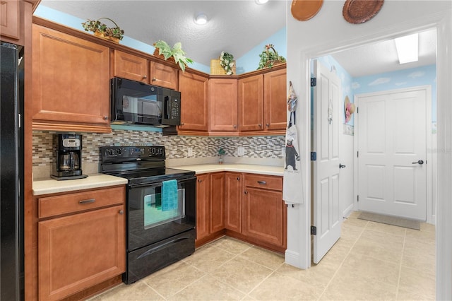 kitchen with backsplash, light tile patterned floors, black appliances, and vaulted ceiling