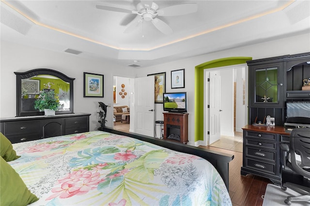 bedroom featuring dark hardwood / wood-style floors, a raised ceiling, and ceiling fan