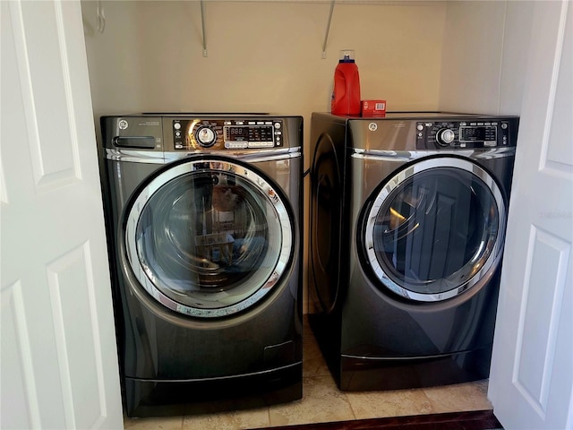 clothes washing area featuring washing machine and clothes dryer and tile patterned floors