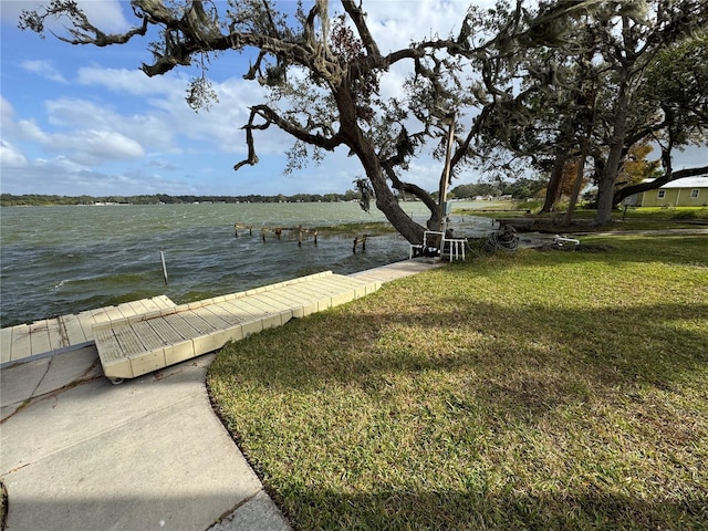 view of dock with a lawn and a water view