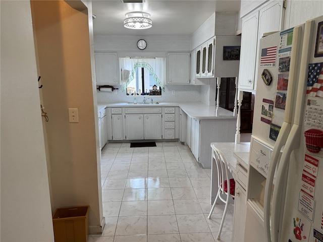 kitchen with white cabinetry, white refrigerator with ice dispenser, and sink