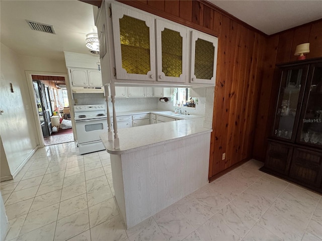 kitchen with wood walls, white cabinetry, electric range, kitchen peninsula, and decorative backsplash