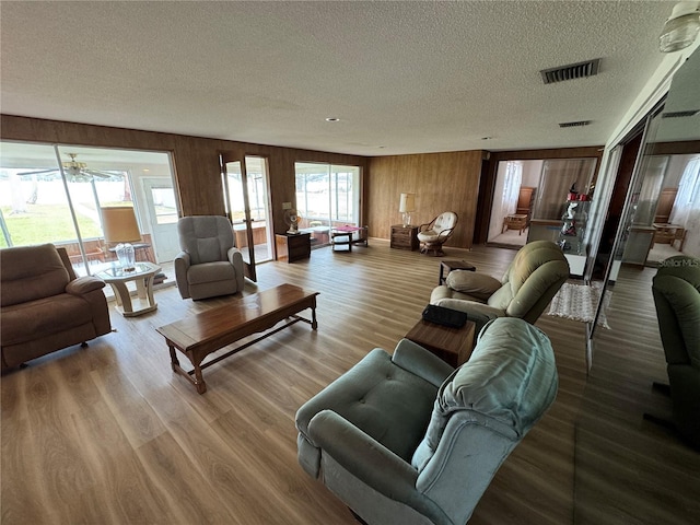 living room with hardwood / wood-style flooring, a textured ceiling, and wood walls