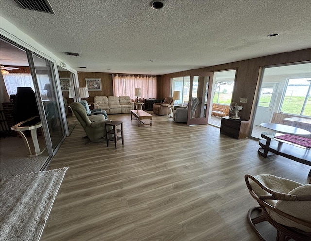 living room with wood walls, wood-type flooring, a textured ceiling, and plenty of natural light