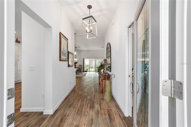 corridor with a notable chandelier and dark hardwood / wood-style floors