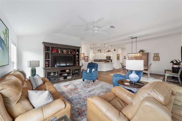 living room with wood-type flooring, vaulted ceiling, and ceiling fan