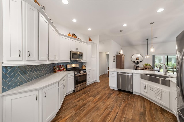 kitchen with appliances with stainless steel finishes, sink, dark hardwood / wood-style floors, white cabinetry, and hanging light fixtures