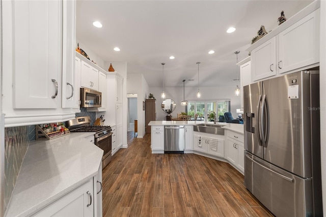 kitchen featuring pendant lighting, dark wood-type flooring, sink, kitchen peninsula, and stainless steel appliances