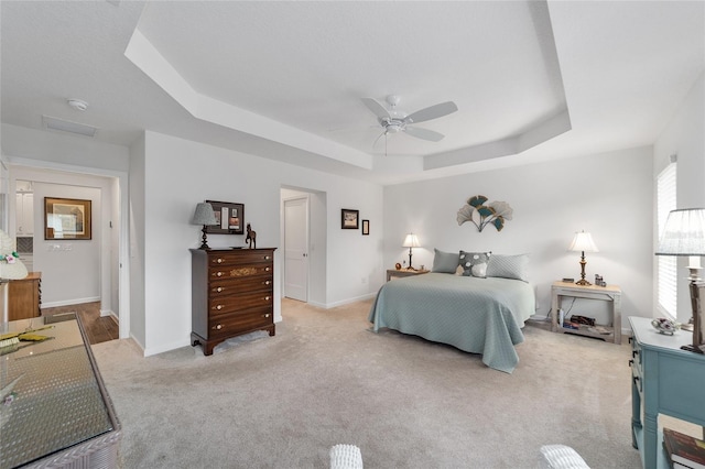 carpeted bedroom featuring ceiling fan and a raised ceiling