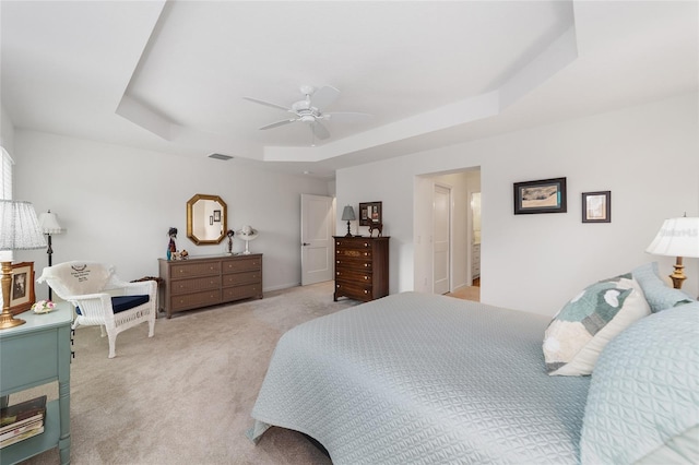 carpeted bedroom featuring a tray ceiling and ceiling fan