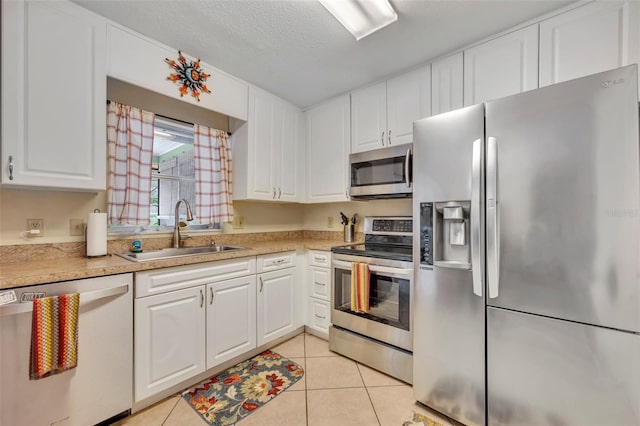 kitchen featuring white cabinets, appliances with stainless steel finishes, light tile patterned flooring, and sink