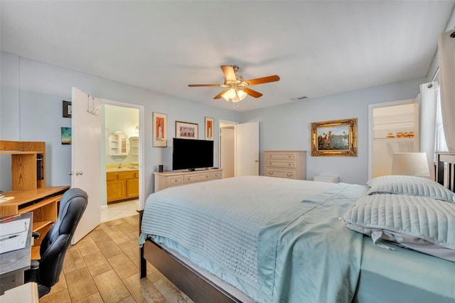 bedroom featuring light wood-type flooring, ensuite bathroom, and ceiling fan