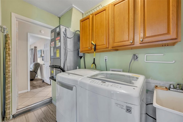 washroom with cabinets, light wood-type flooring, independent washer and dryer, and sink