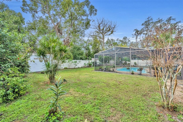 view of yard with a fenced in pool and glass enclosure