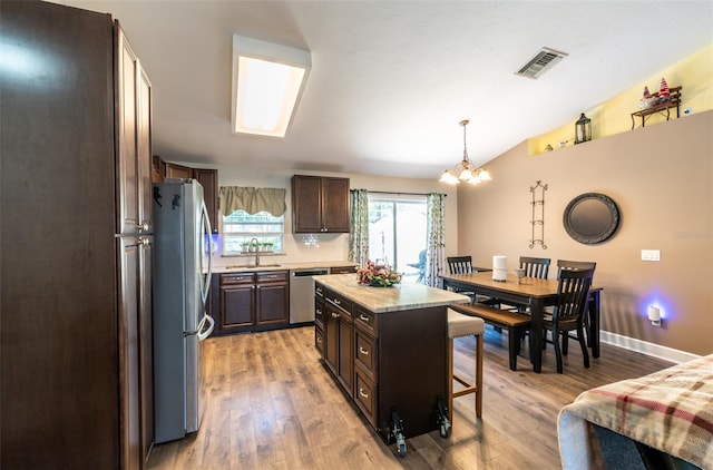 kitchen featuring sink, a center island, pendant lighting, appliances with stainless steel finishes, and light wood-type flooring