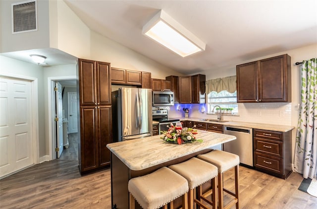 kitchen with a center island, sink, light hardwood / wood-style flooring, appliances with stainless steel finishes, and a breakfast bar area