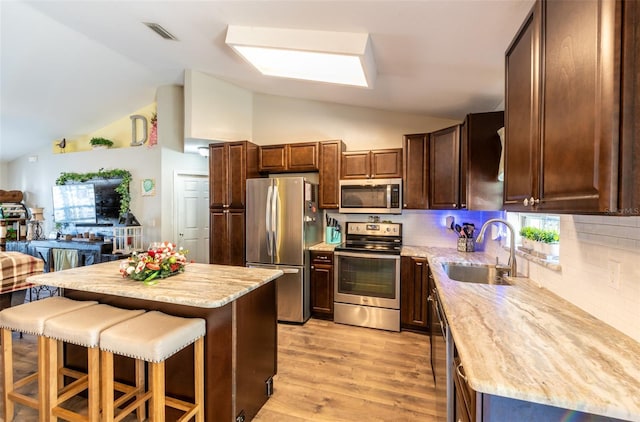 kitchen featuring a center island, lofted ceiling with skylight, sink, light hardwood / wood-style floors, and stainless steel appliances