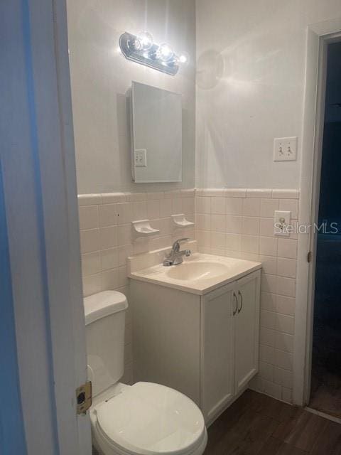 bathroom featuring hardwood / wood-style floors, vanity, toilet, and tile walls