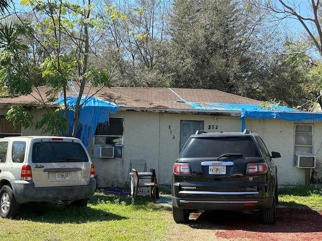 view of side of home featuring a shingled roof, a yard, and stucco siding