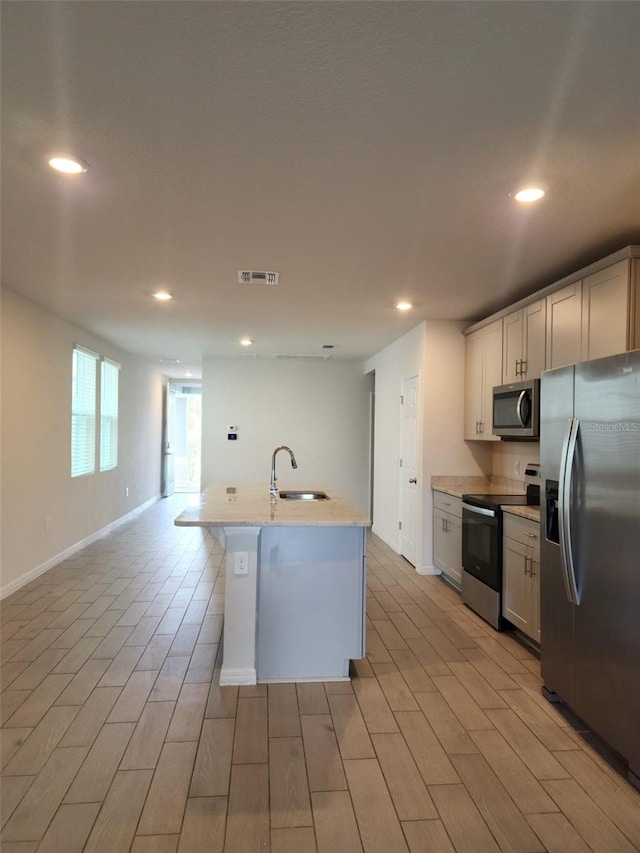 kitchen with stainless steel appliances, light hardwood / wood-style flooring, and sink