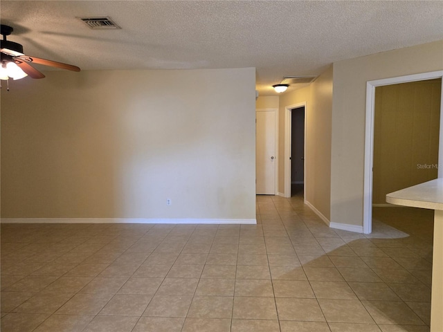 tiled spare room with ceiling fan and a textured ceiling