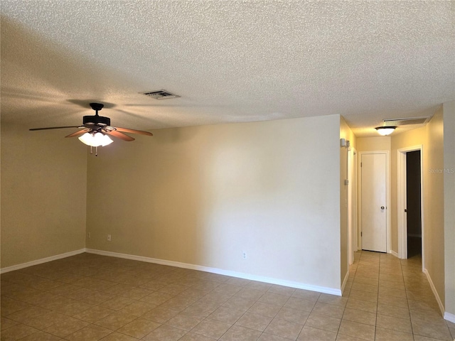 spare room featuring ceiling fan, light tile patterned floors, and a textured ceiling