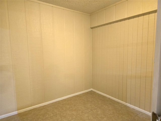 unfurnished room with wood walls and a textured ceiling