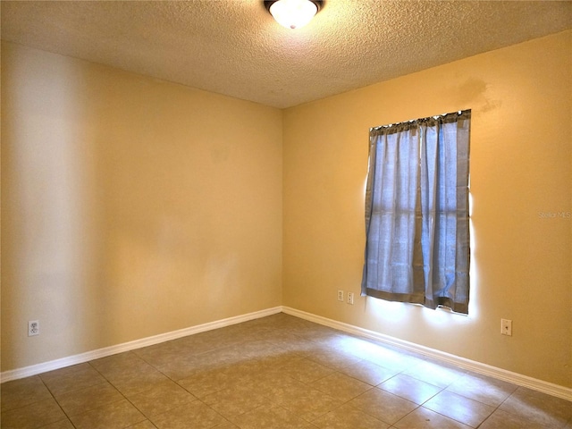 tiled spare room featuring a textured ceiling